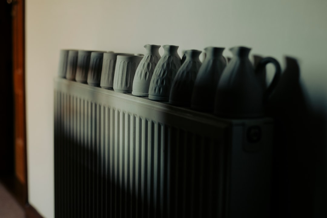 Row of white ceramic vases on a radiator.