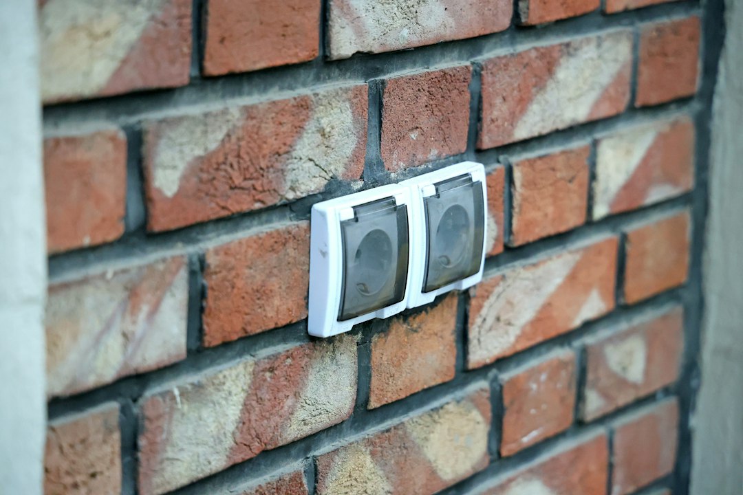Two white electrical outlets with protective covers mounted on a red brick wall