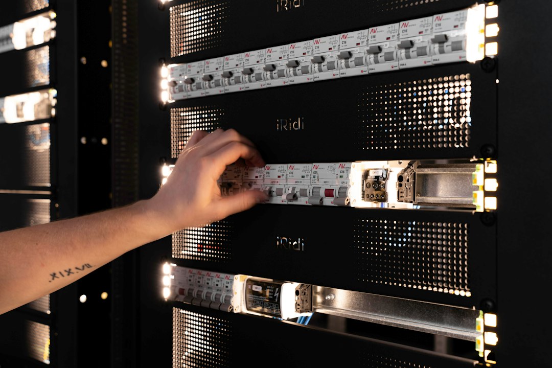A hand adjusting components in a glowing server rack
